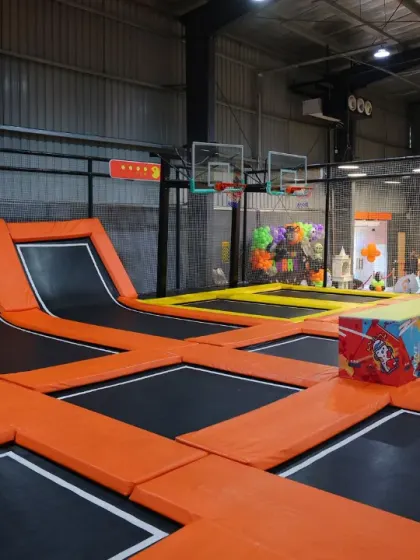 A view of the different sections within our trampoline park, including areas for free jumping and structures for interactive play. The entire zone is enclosed with high safety nets.