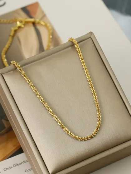 A sparkling double-strand necklace with a textured finish, displayed in its gift box. This piece is perfect for adding a touch of glamour.