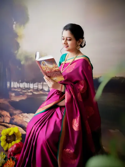 A traditional and contemplative portrait. The mom-to-be, dressed in a beautiful silk saree, is reading, creating a peaceful and classic image.
