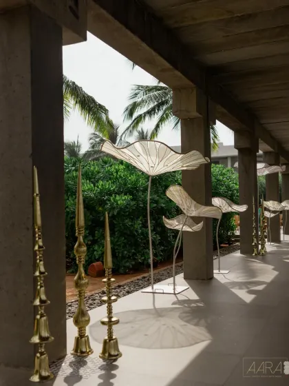 Sculptural white lotuses and brass lamps line the walkway of this modern engagement venue. These artistic elements add a touch of magic and sophistication to the serene waterside setting.
