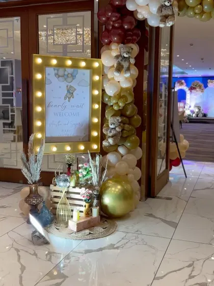 A "Bearly wait to welcome you" light-up sign at the entrance of a baby shower, paired with rustic and boho decor elements.