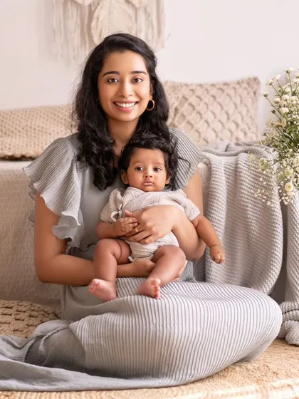 A mother sits with her baby boy in a beautifully styled studio. The vase of baby's breath flowers adds a delicate and elegant touch to the scene.