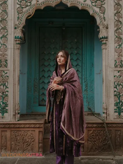 A beautiful, soulful portrait of the bride in her traditional velvet outfit. The intricate details of the doorway and her thoughtful expression make this a captivating image.