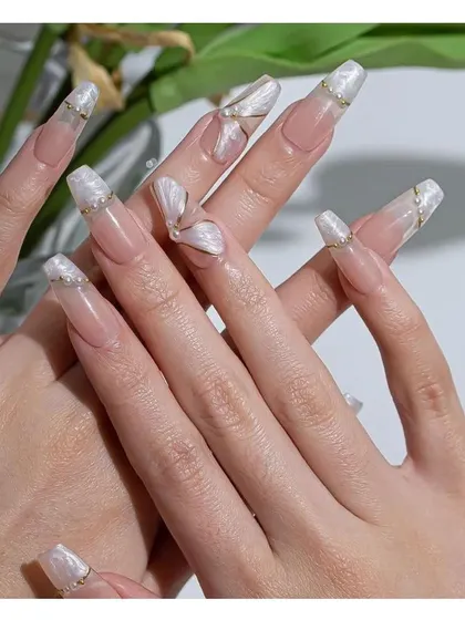 Ethereal and elegant, these long coffin nails feature a pearly white base with delicate 3D sculpted details, gold foil, and gold line accents for a truly artistic look.