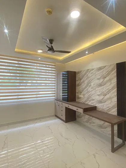 A bedroom study nook featuring a marble-finish accent wall and a custom-designed desk. The false ceiling with cove lighting adds a touch of luxury to this functional space.