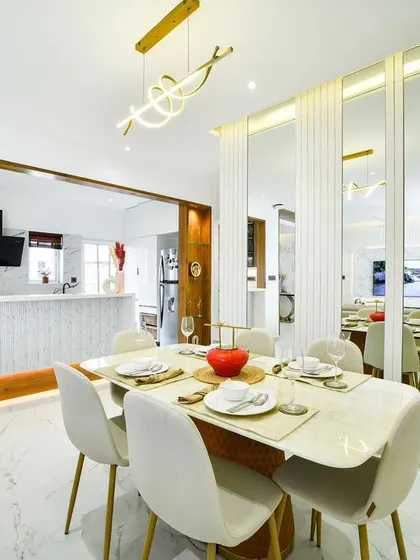 A bright and refined dining area where mirrored wall panels and a modern swirl chandelier create a sense of spaciousness and flair. The open-pass through to the kitchen enhances the connected feel.