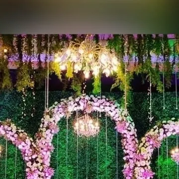 Lighting is crucial for setting the mood. In this reception setup, I used elegant mini-chandeliers hanging at different heights against a green wall to create a dreamy, enchanting forest effect.