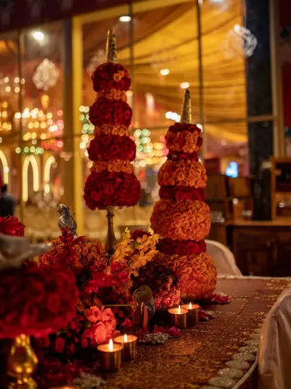 The warm glow of candles illuminates the intricate floral towers, creating a dramatic and festive atmosphere for the evening celebration.