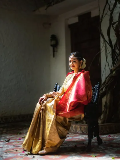A quiet, seated portrait of a bride in a traditional setting. The soft light from the side and her elegant pose create a timeless and graceful image.