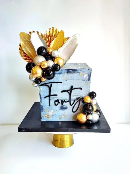 A sophisticated square cake for a 40th birthday. The textured blue-grey finish with black, gold, and silver spheres creates a modern and masculine look.