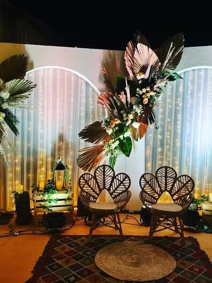 A unique and artistic stage backdrop for a bohemian-themed event. We used dried palm leaves, pampas grass, and fresh flowers to create a textured and visually stunning focal point.