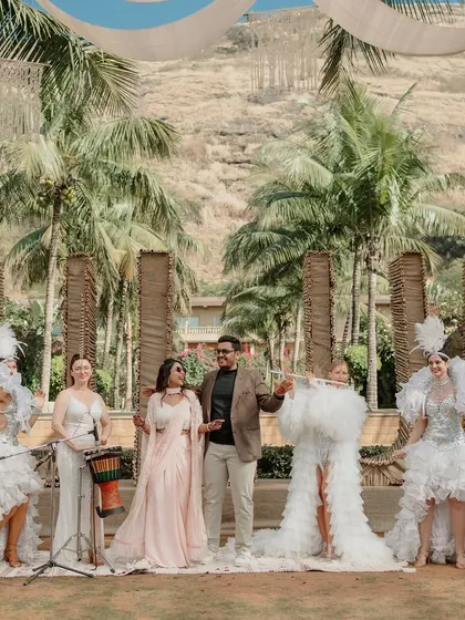 The couple posing with the live band and performers at their Tulum-themed welcome lunch.