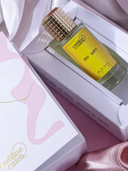 This shot focuses on the perfume and its elegant packaging. The soft, silky fabric and clean lighting give it a premium, giftable quality, ideal for unboxing features.