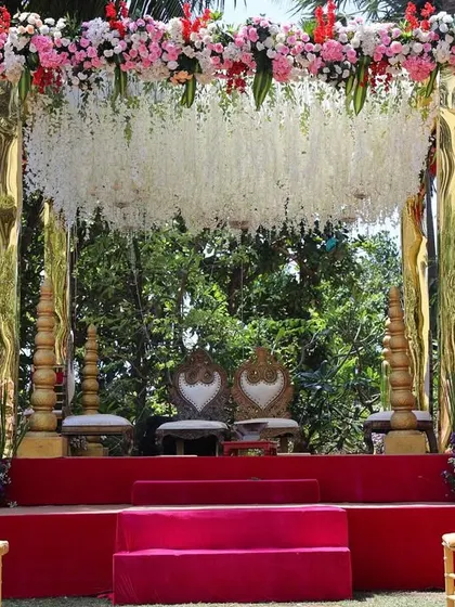 A close-up of a beautiful mandap with a cascading floral chandelier. The combination of white flowers and lush greenery against the gold structure creates a fresh and elegant look.