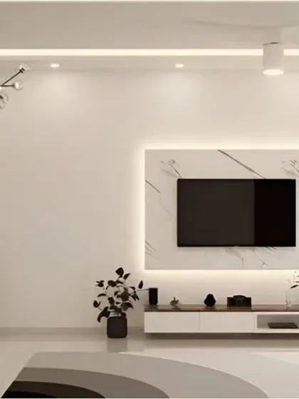 A minimalist living room where the TV unit is the star. The clean white console and marble panel are complemented by a tall wooden display shelf.