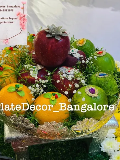 A mixed fruit platter with decorated apples, oranges, and sweet limes, showcasing a variety of decoration styles in one arrangement.