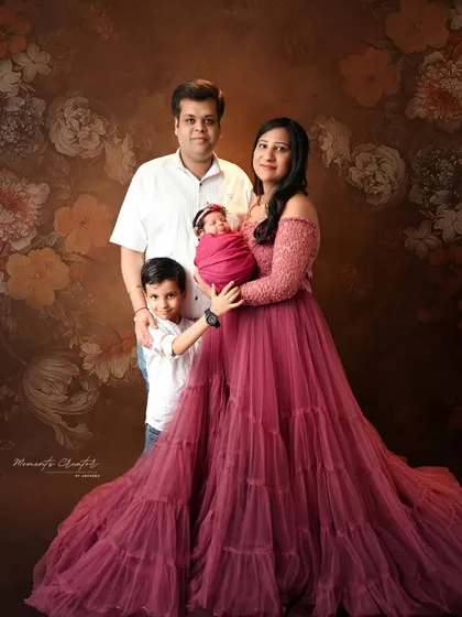 A complete family portrait with their new baby girl. The big brother stands proudly beside his parents, creating a lovely memory of their new family of four.