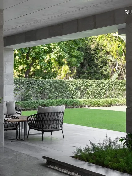 A covered walkway at the entrance provides a seamless transition from the outdoors, with views into the lush side lawn, blurring the lines between the home and its landscape.
