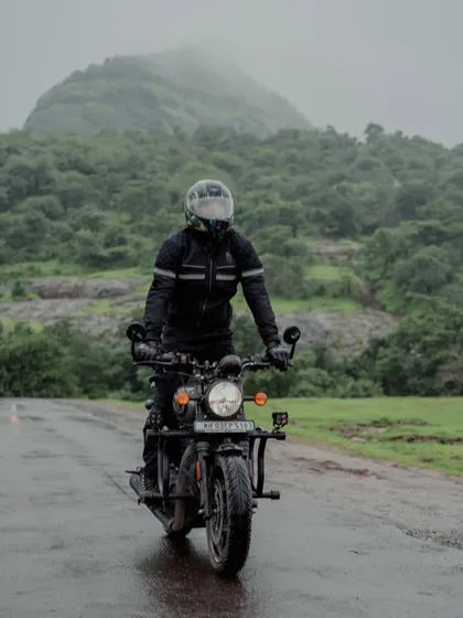 Me riding my motorcycle on a wet road with lush green hills in the background. This photo embodies the classic monsoon road trip experience in the Western Ghats.