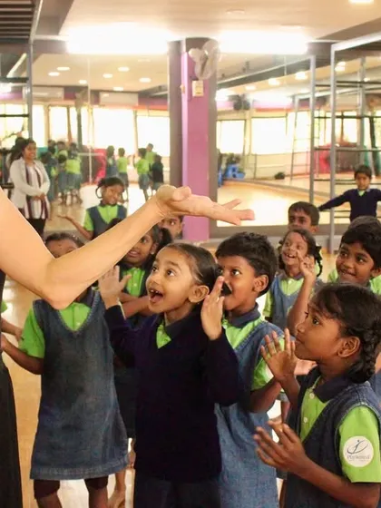 A teacher engages with an animated group of students. The dynamic interaction and shared energy make these classes special.