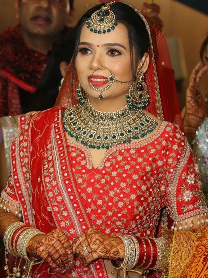 A close-up portrait that highlights the flawless base and the beautiful green and gold jewelry.