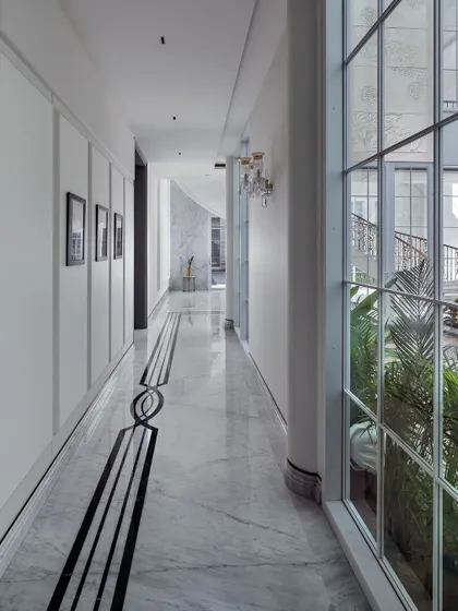 This view highlights the exquisite details of the corridor, with its intricate black and white marble inlay flooring and classic wall paneling. Every element is designed to guide the eye and create a sense of elegant, flowing movement through the home.
