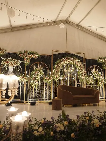 Another angle of the sophisticated tented reception stage, highlighting the warm glow of the candelabras and chandeliers against the dark, elegant backdrop.