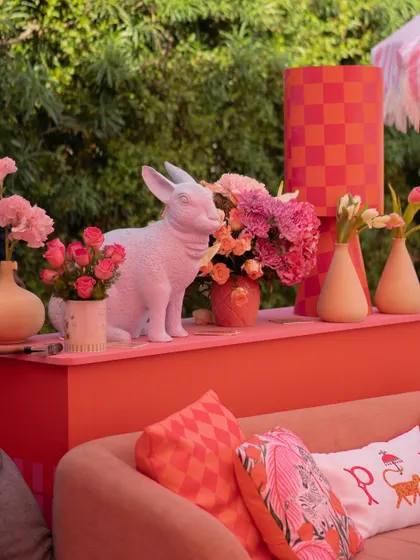 A close-up of the whimsical decor, featuring a white rabbit prop, a checkerboard lamp, and beautiful arrangements of pink flowers.