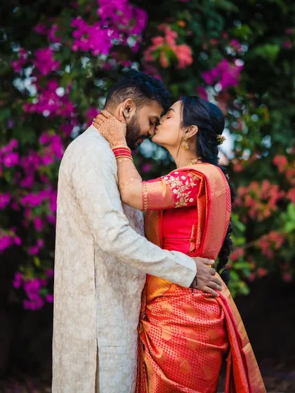 A sweet kiss against a vibrant wall of flowers. This intimate moment from Devika and Laukik's engagement is full of color and romance.
