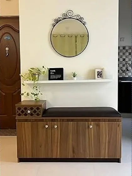 A simple and practical entryway with a wooden shoe cabinet that doubles as a bench. The floating shelf and mirror above help to make the space feel open and organized.