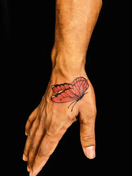 After: We brought the butterfly to life with vibrant red and orange shading. This rework turned a simple outline into a beautiful, eye-catching color tattoo.