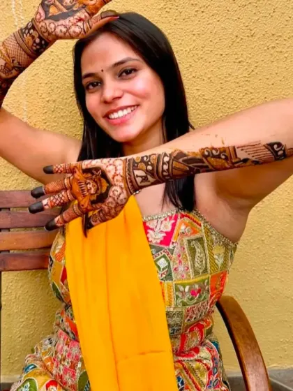 A joyful bride posing with her intricate storytelling mehandi.