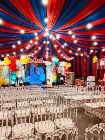 A full venue transformation for a grand carnival themed birthday party. We used bold red and blue ceiling drapes to create a 'big top' tent effect, complete with themed stalls and festive lighting for an immersive experience.