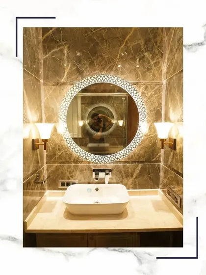 This bathroom vanity area is a perfect example of refined extravagance, with its decorative mirror, warm sconce lighting, and beautiful marble countertop.