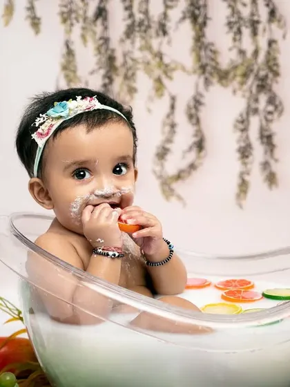 A sweet treat after a fun splash. This little one enjoys a bite of fruit during her milk bath session, showing the playful and unique photo opportunities we can create.