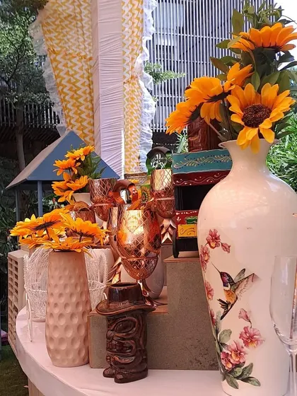 A close-up on the vibrant decor, featuring a beautiful vase with hummingbird illustrations, bright sunflowers, and elegant copper-toned glasses.