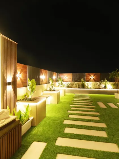 A perspective shot showing the illuminated pathway leading past the Buddha statue towards the main seating area in Sushant Lok.