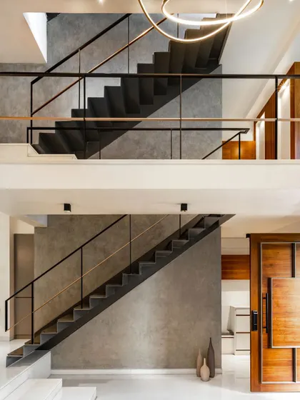 The interior of the SOL House features a multi-level steel staircase that echoes the home's exterior frame. The design creates a series of interconnected spaces with varying heights and visual connections, resulting in a dynamic interior experience.
