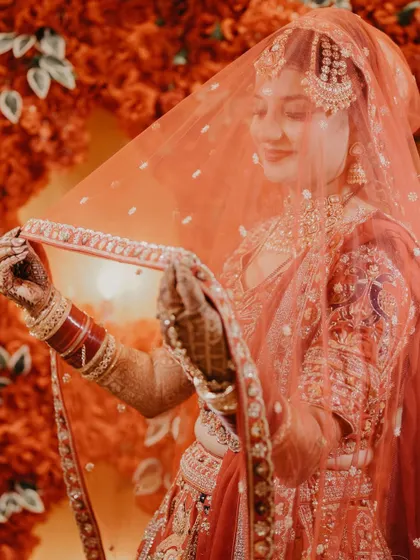A stunning portrait of a Sikh bride, her face softly lit through her red veil. This image is all about grace, color, and tradition.