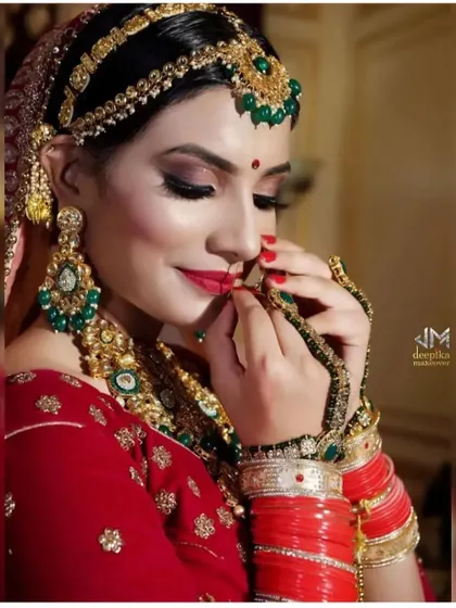 A close-up of a bride adjusting her nath, with her hair styled in a secure and elegant bun. This shows how a good hairstyle complements every part of the bridal attire.