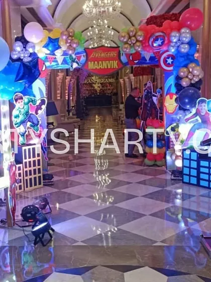 A grand superhero entrance, with an aisle lined with cutouts of various heroes like Superman, Hulk, and Captain America.