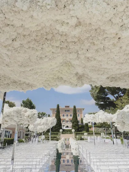 Looking out from under the floral cloud canopy of the Cannes wedding, the design perfectly frames the magnificent château in the distance, blending the decor with the stunning location.