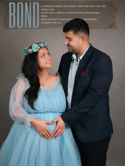 Titled 'Bond', this image captures the deep connection between the expecting parents. They share a loving look as they both hold the baby bump, her in a beautiful blue gown and floral crown.