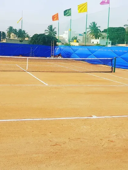 This wide shot shows the full expanse of one of our courts, with the net properly tensioned and the playing area clear. The surrounding flags and greenery add to the classic club feel of our facility.