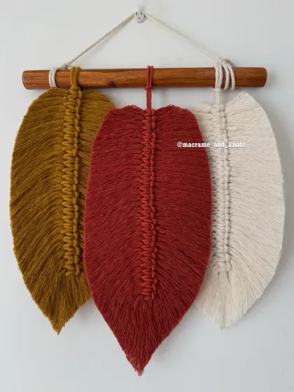 This simple feather wall hanging with three leaves in rust, mustard, and cream is perfect for a minimal, bohemian look.