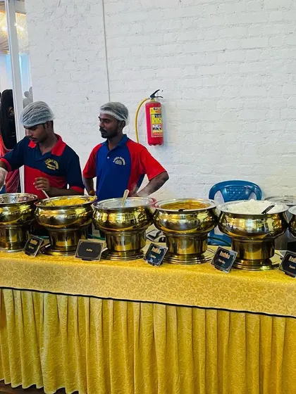 Our staff ready to serve at a wedding buffet. We offer a mix of veg and non-veg dishes, clearly labeled, so guests can choose according to their preference. The golden serving bowls add a touch of elegance.