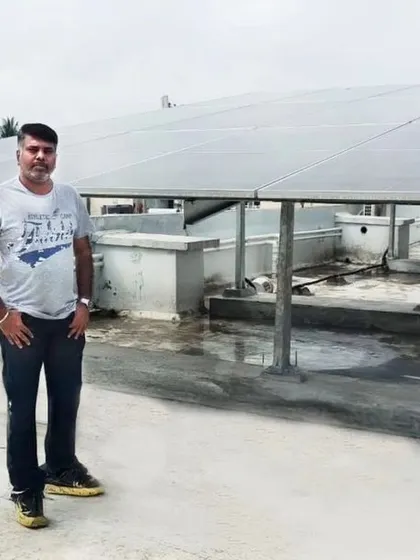 A resident of Adithya Elixir Housing Society in Bangalore poses in front of his new, expansive solar panel system.