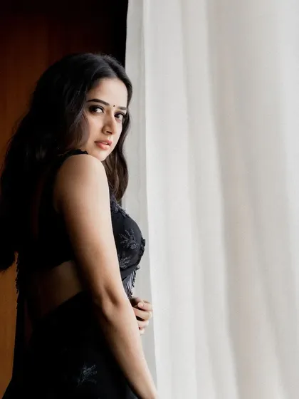 A side view showing the elegant drape of the black georgette saree and the unique detailing on the blouse strap. It's a timeless piece for any formal evening event.