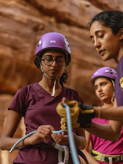 An instructor carefully guides a participant as she learns to tie a figure-eight knot. This hands-on teaching is crucial for building confidence with rope skills.