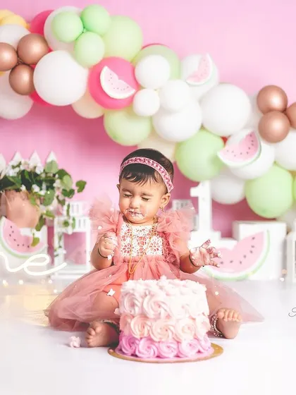 A one-year-old girl enjoying her pretty pink cake during a watermelon-themed birthday smash.